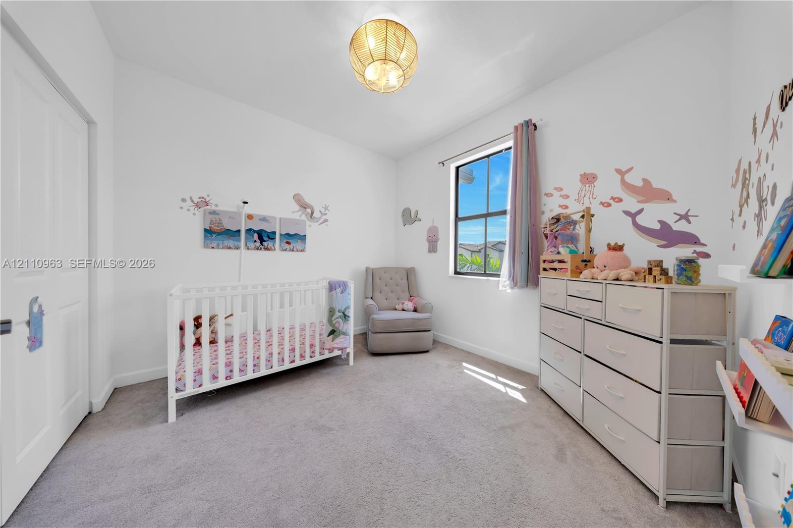 Neutral-toned carpeting, single-hung window with dark framing, and a central spherical light fixture with a metallic finish