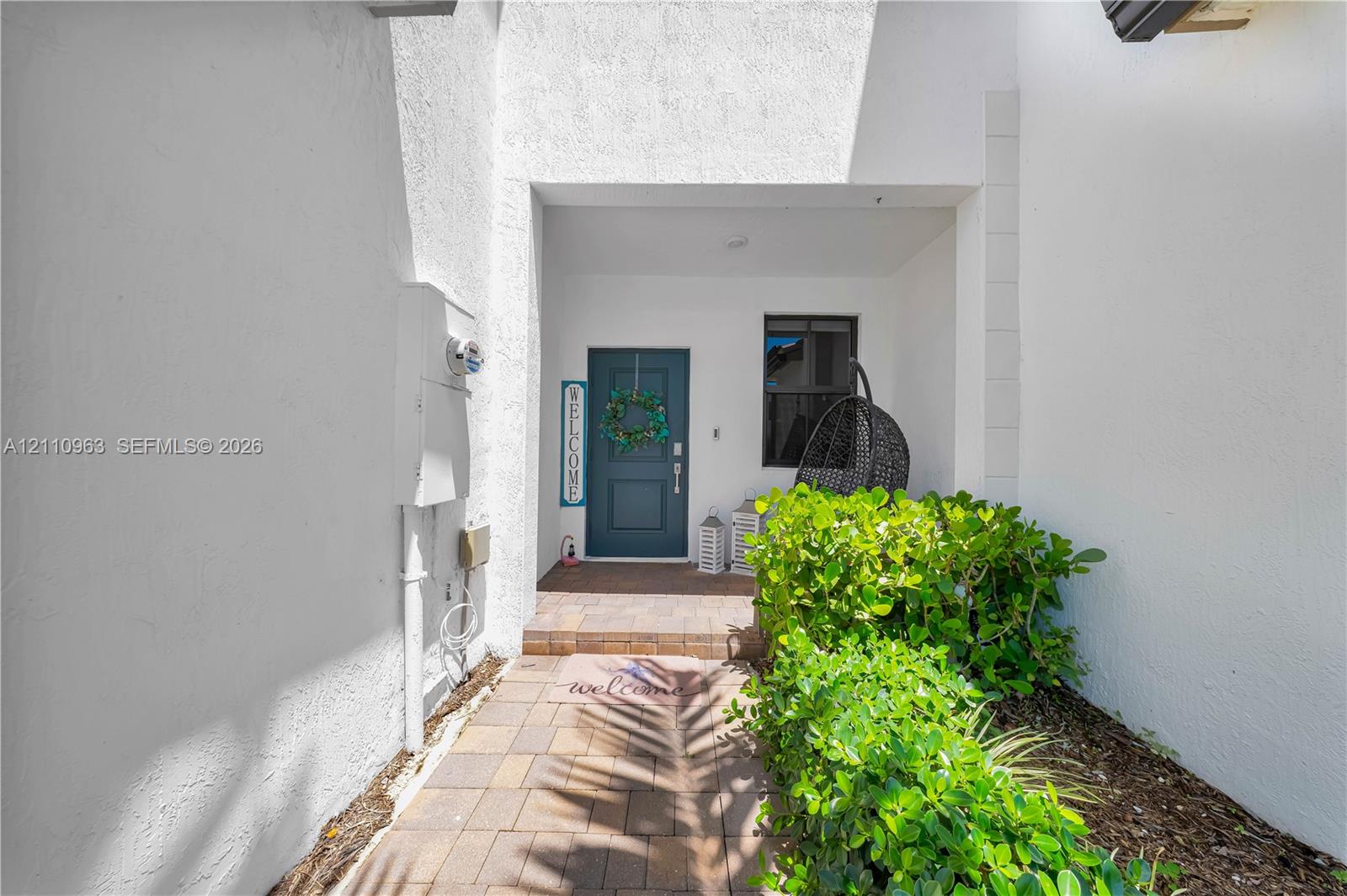 Recessed entryway featuring stucco exterior walls, paved brick walkway, and a paneled entry door