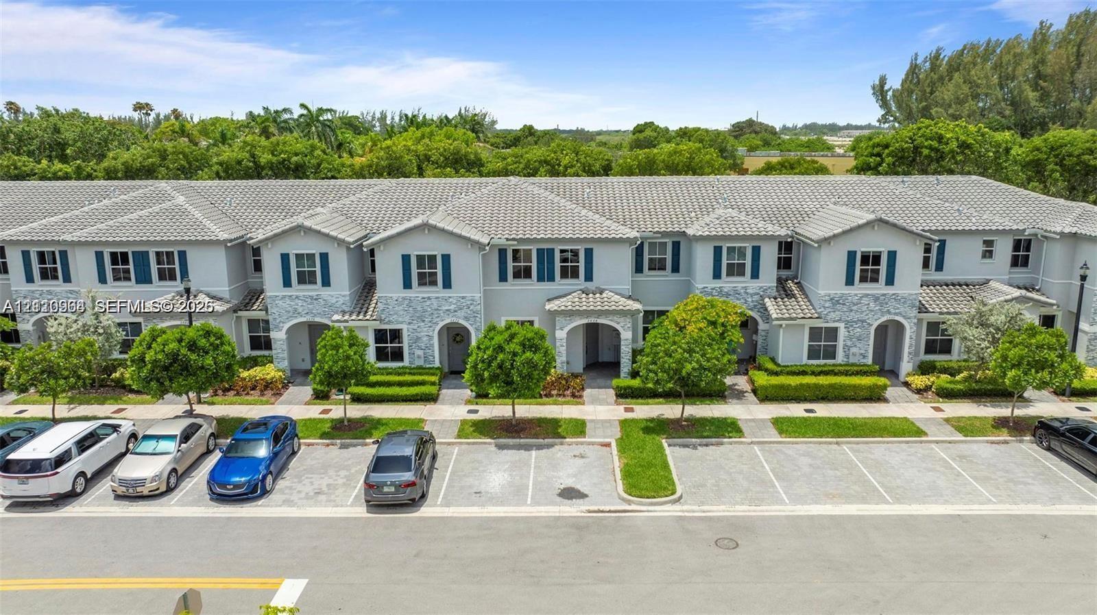 Two-story townhouse exterior featuring a concrete tile roof, stone facade accents, shuttered windows, and dedicated surface parking Two-story townhouse exterior featuring a concrete tile roof, stone facade accents, shuttered windows, and dedicated surface parking