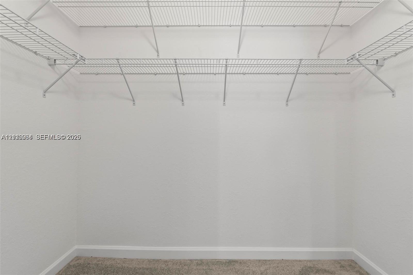 Walk-in closet featuring floor-to-ceiling white walls and white wire shelving