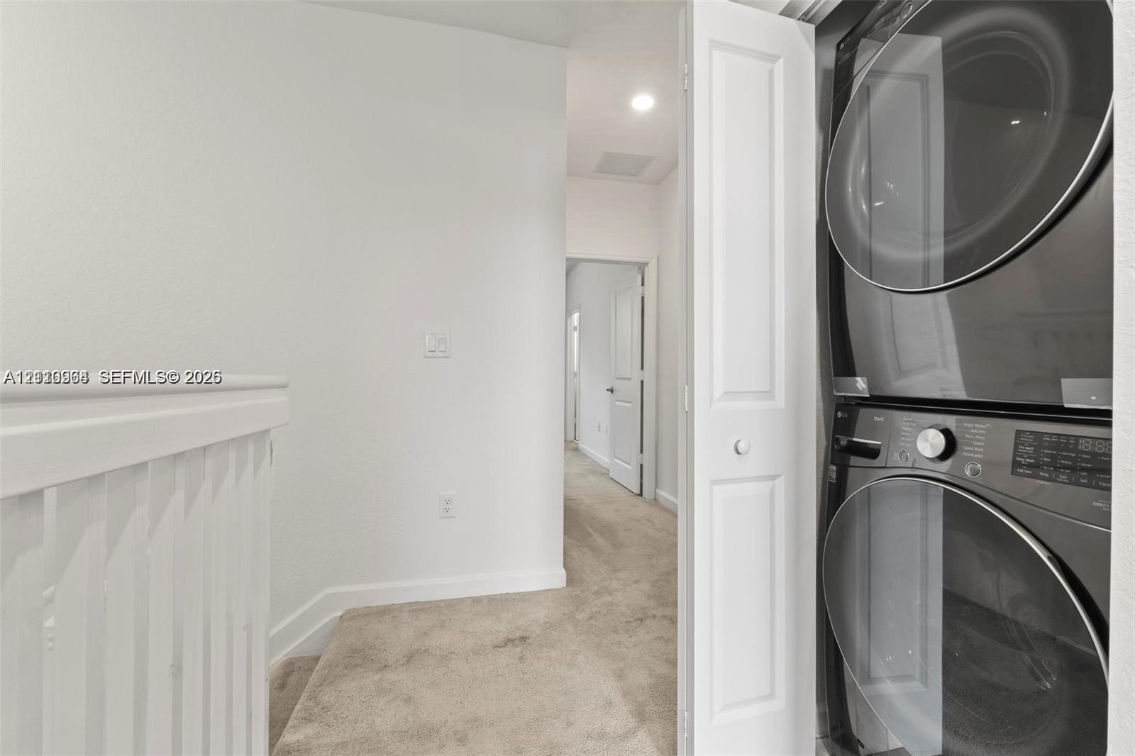 Stacked front-load laundry appliances housed within a closet featuring a bi-fold door