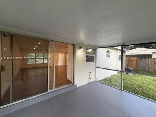 Enclosed patio featuring a solid ceiling, painted concrete flooring, wall-mounted light fixture, and large sliding glass door entry
