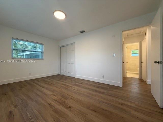 Room featuring wood-finish flooring, a flush-mount ceiling light, and a sliding-door closet