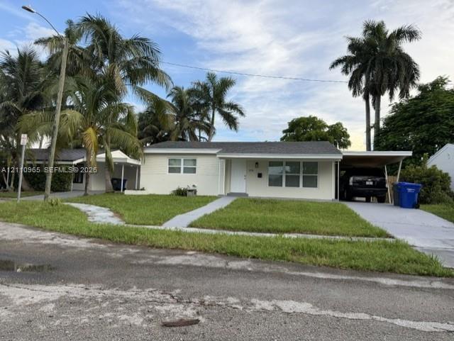 Single-story residence featuring light-toned brick exterior, asphalt shingle roof, integrated carport, and mature palm trees Single-story residence featuring light-toned brick exterior, asphalt shingle roof, integrated carport, and mature palm trees