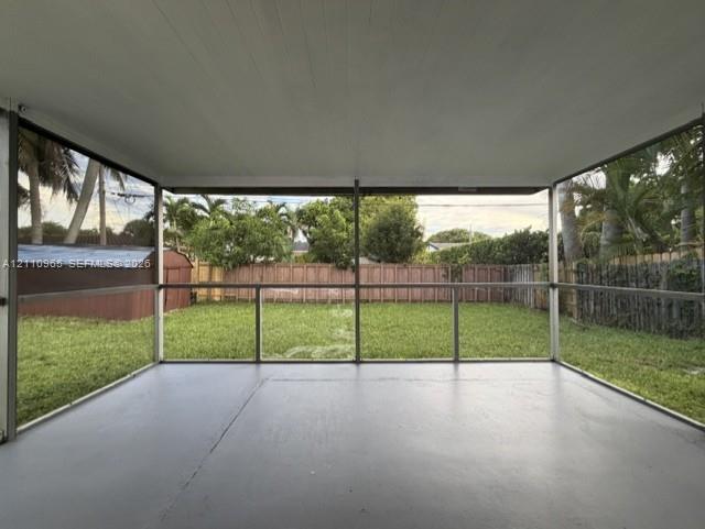 Screened-in porch featuring a concrete floor, painted ceiling, and panoramic mesh screening overlooking a fenced backyard Screened-in porch featuring a concrete floor, painted ceiling, and panoramic mesh screening overlooking a fenced backyard