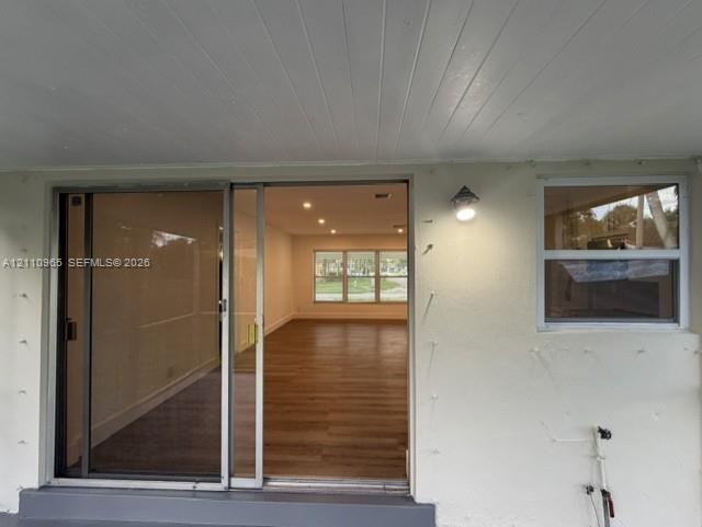 Covered exterior entryway featuring a sliding glass door, single-pane window, recessed ceiling lighting, and wood-finish flooring visible within the interior Covered exterior entryway featuring a sliding glass door, single-pane window, recessed ceiling lighting, and wood-finish flooring visible within the interior