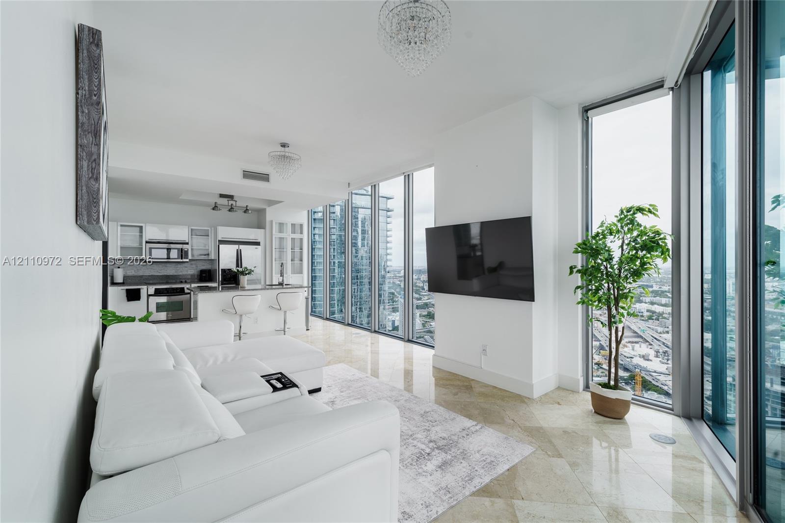 Floor-to-ceiling windows, polished stone tile flooring, stainless steel appliances, white cabinetry, and crystal-style chandelier lighting Floor-to-ceiling windows, polished stone tile flooring, stainless steel appliances, white cabinetry, and crystal-style chandelier lighting