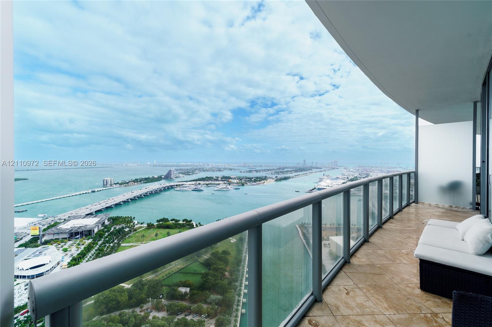 Spacious covered balcony with stone-finish flooring and a glass-paneled railing Spacious covered balcony with stone-finish flooring and a glass-paneled railing