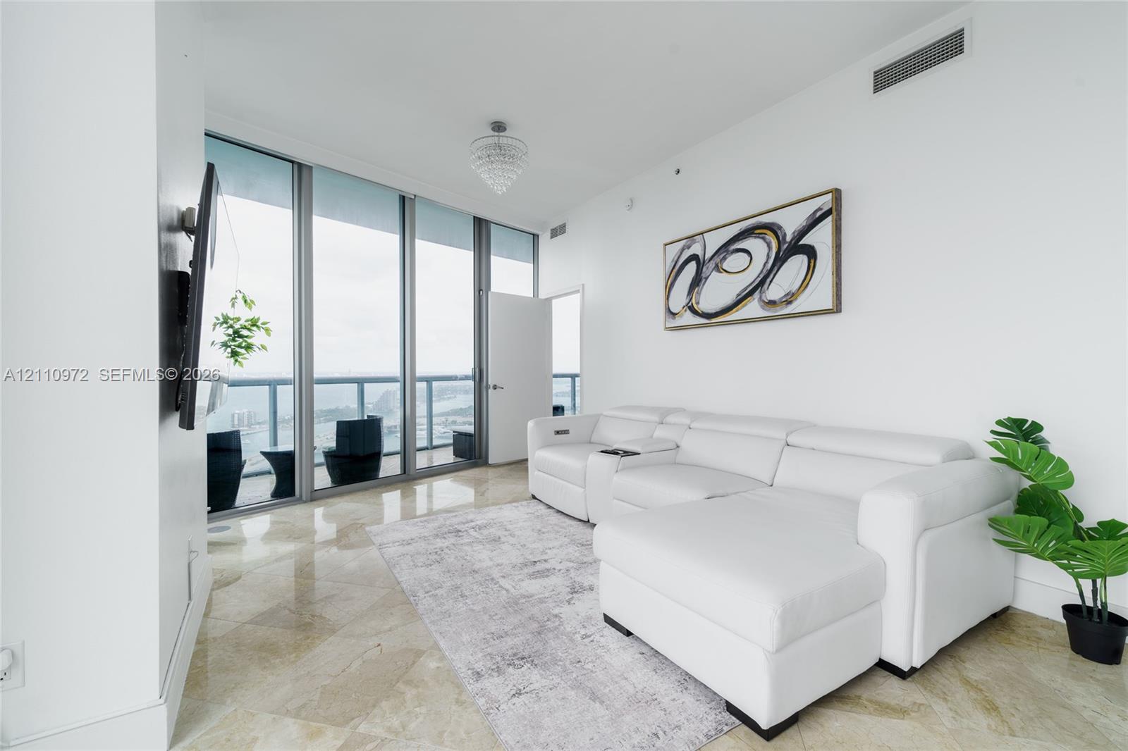 Floor-to-ceiling glass panel walls, polished stone flooring, recessed ceiling lighting, and private glass-railing balcony
