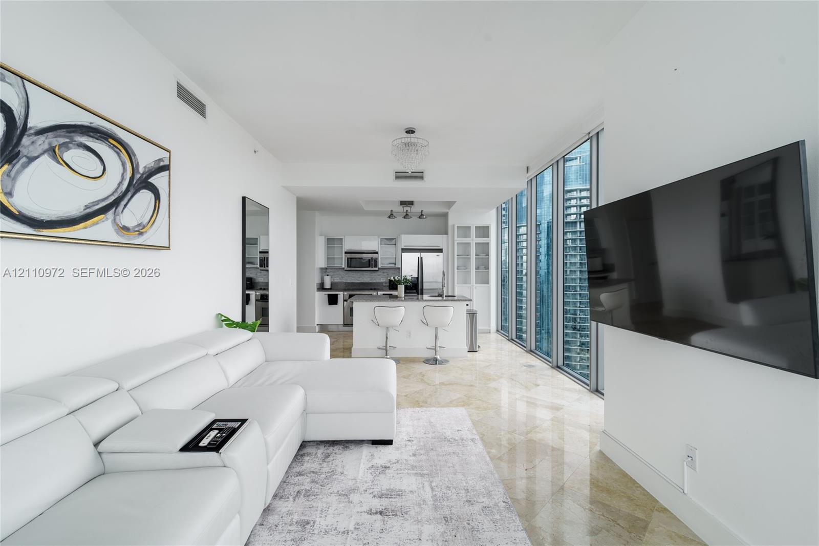 Polished stone flooring, floor-to-ceiling windows, modern kitchen with stainless steel appliances, and built-in glass cabinetry