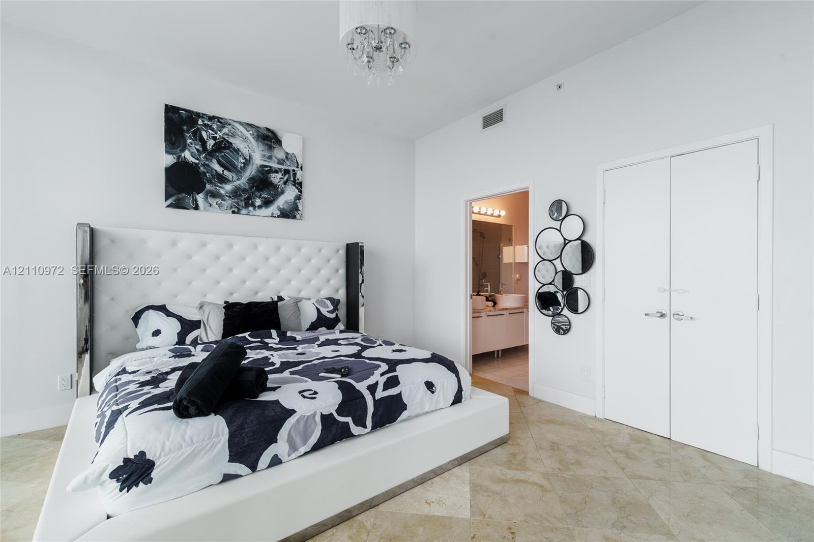 High ceilings featuring a drum-style chandelier, stone flooring, and dual-door closet