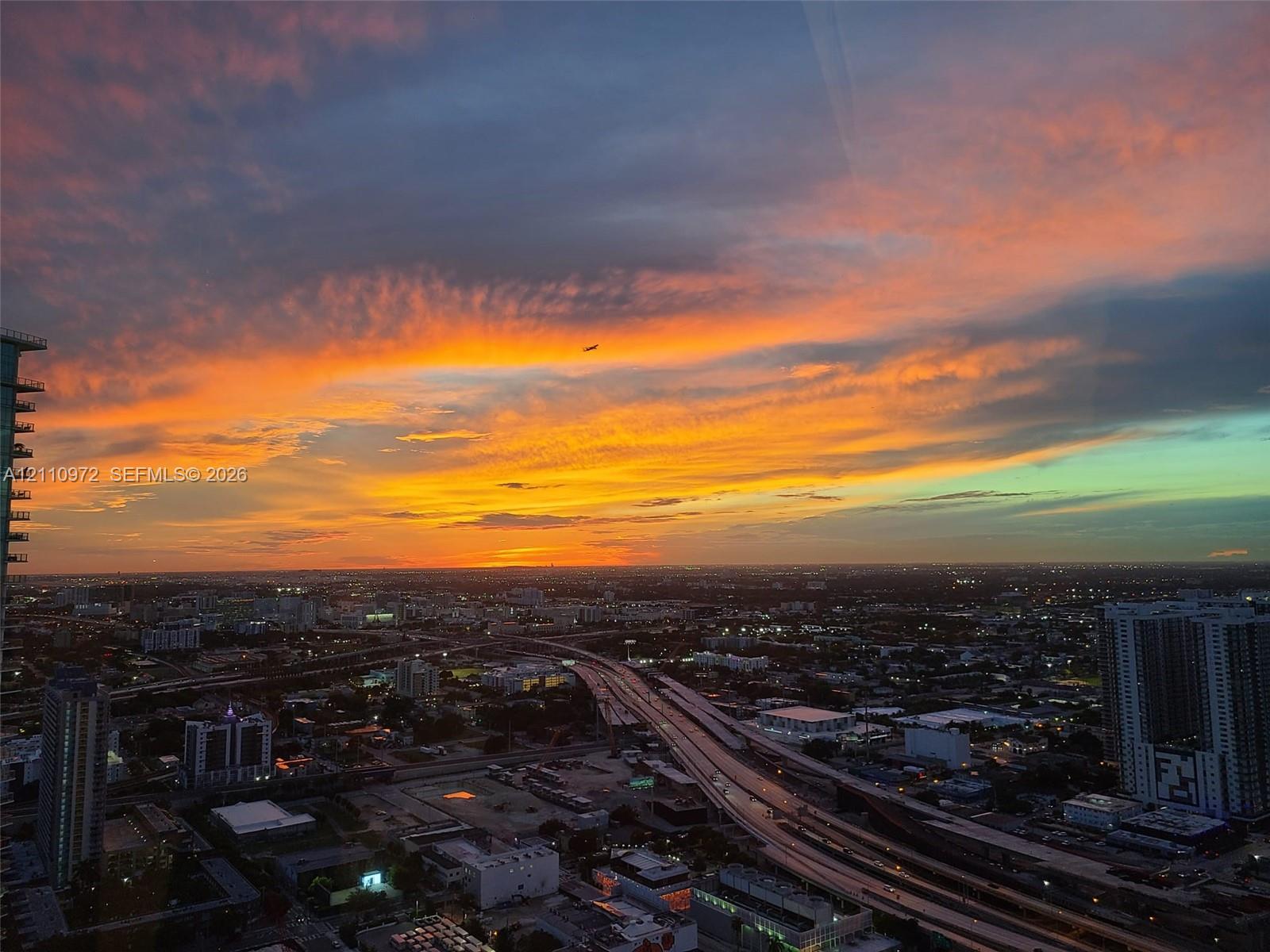Elevated panoramic cityscape featuring a sunset backdrop