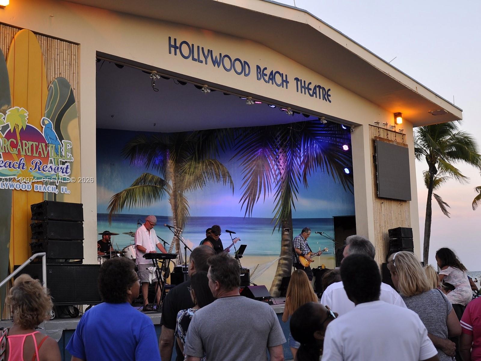Outdoor entertainment venue featuring a covered stage, integrated sound system, bamboo-paneled siding, and a mural backdrop