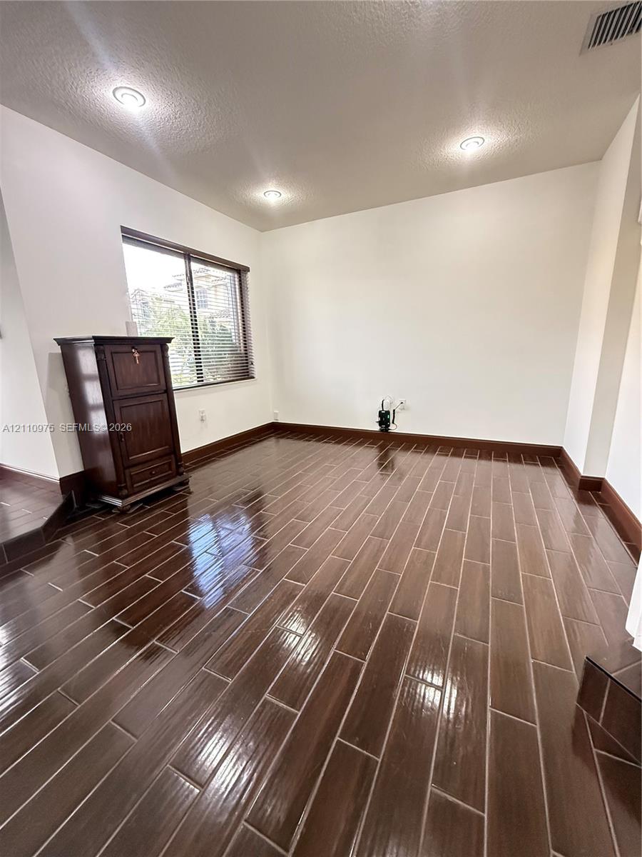 Glossy wood-finish tile flooring, recessed ceiling lighting, and a window with horizontal blinds