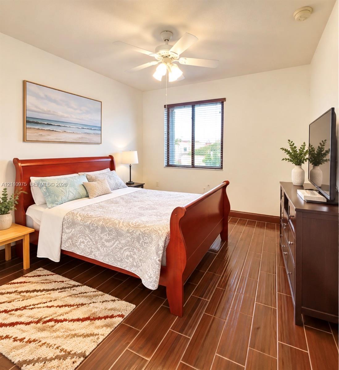 Room featuring wood-finish tile flooring, ceiling fan with light fixture, and horizontal blinds