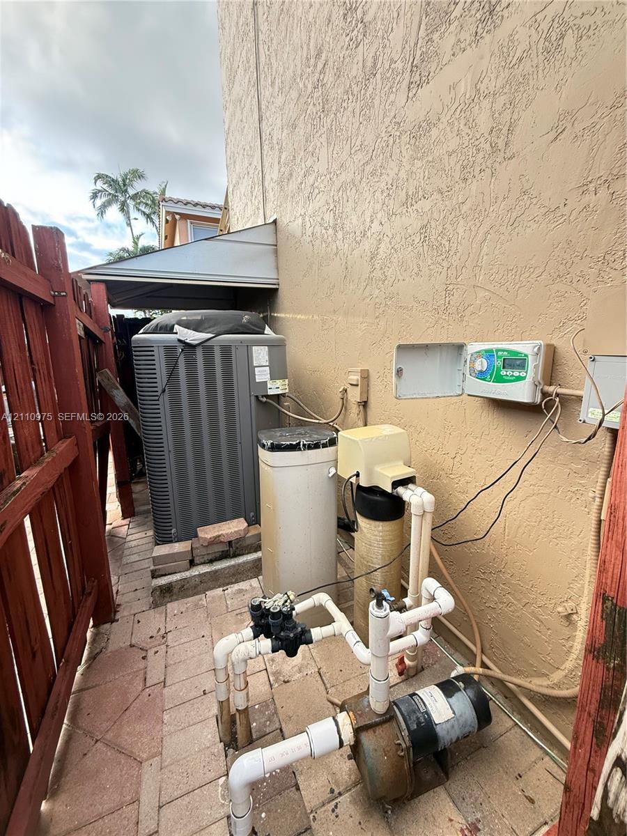 Exterior area featuring a central air conditioning unit, water filtration system, and irrigation pump set on a paver foundation