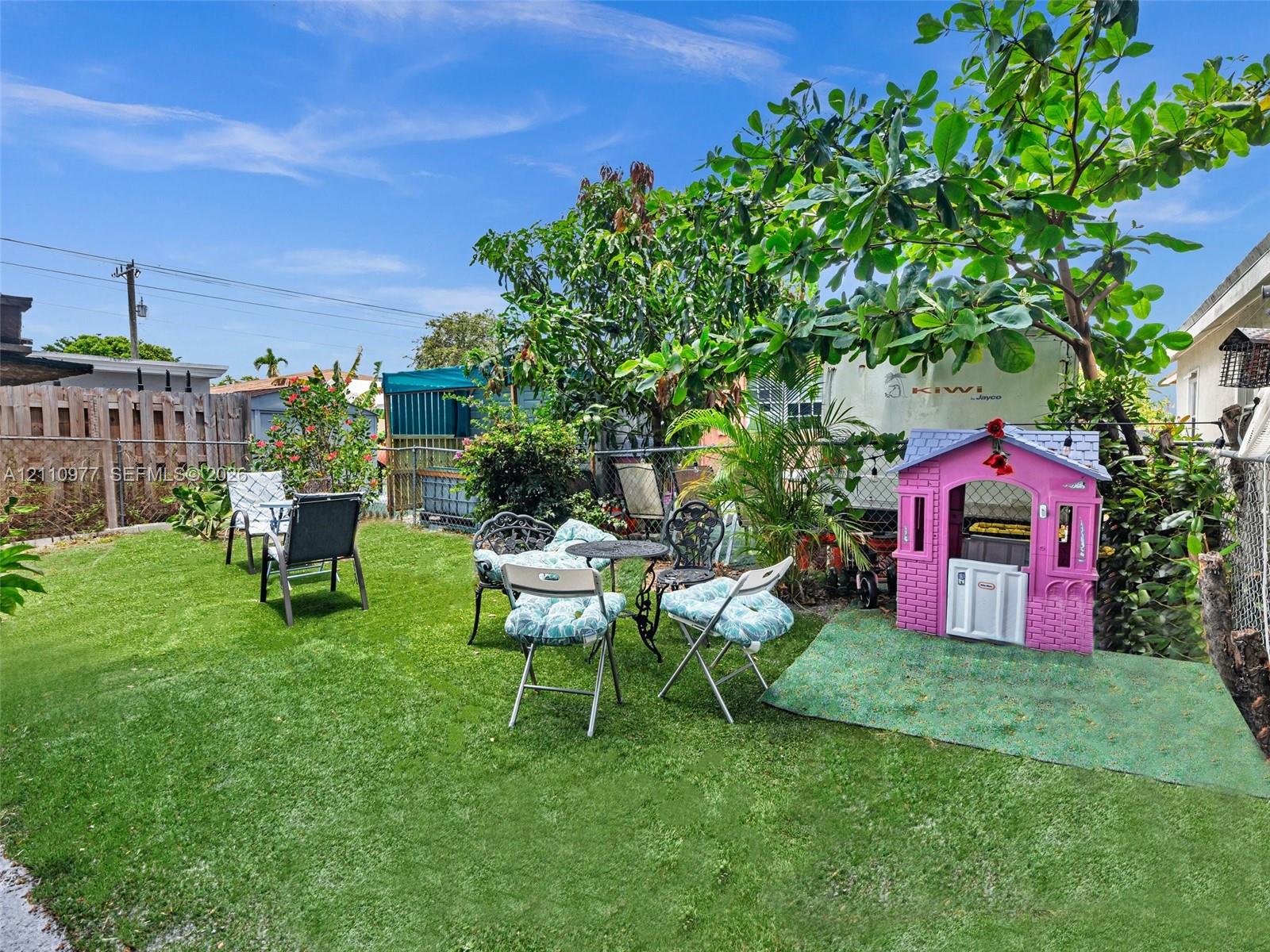 Backyard space featuring synthetic turf, perimeter fencing, and mature trees