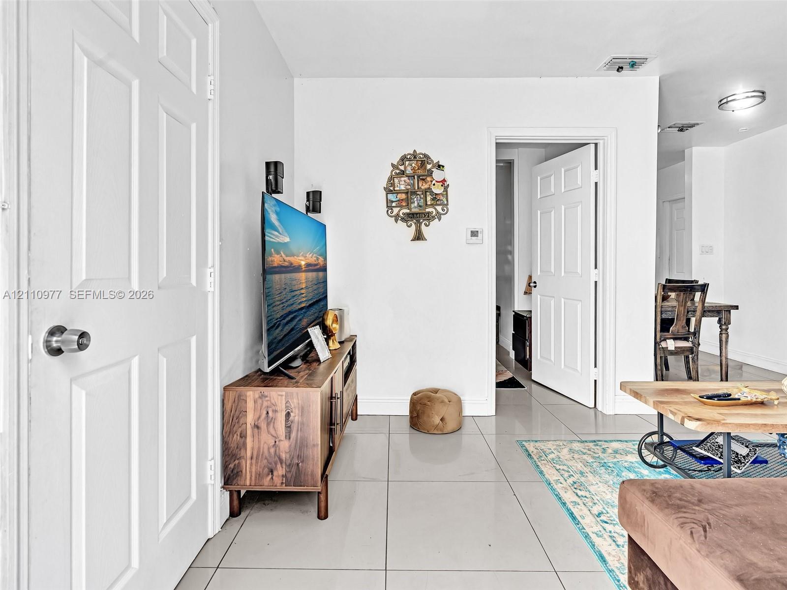 Interior space featuring large-format ceramic tile flooring, neutral wall finishes, and solid-core six-panel interior doors with brushed metal hardware