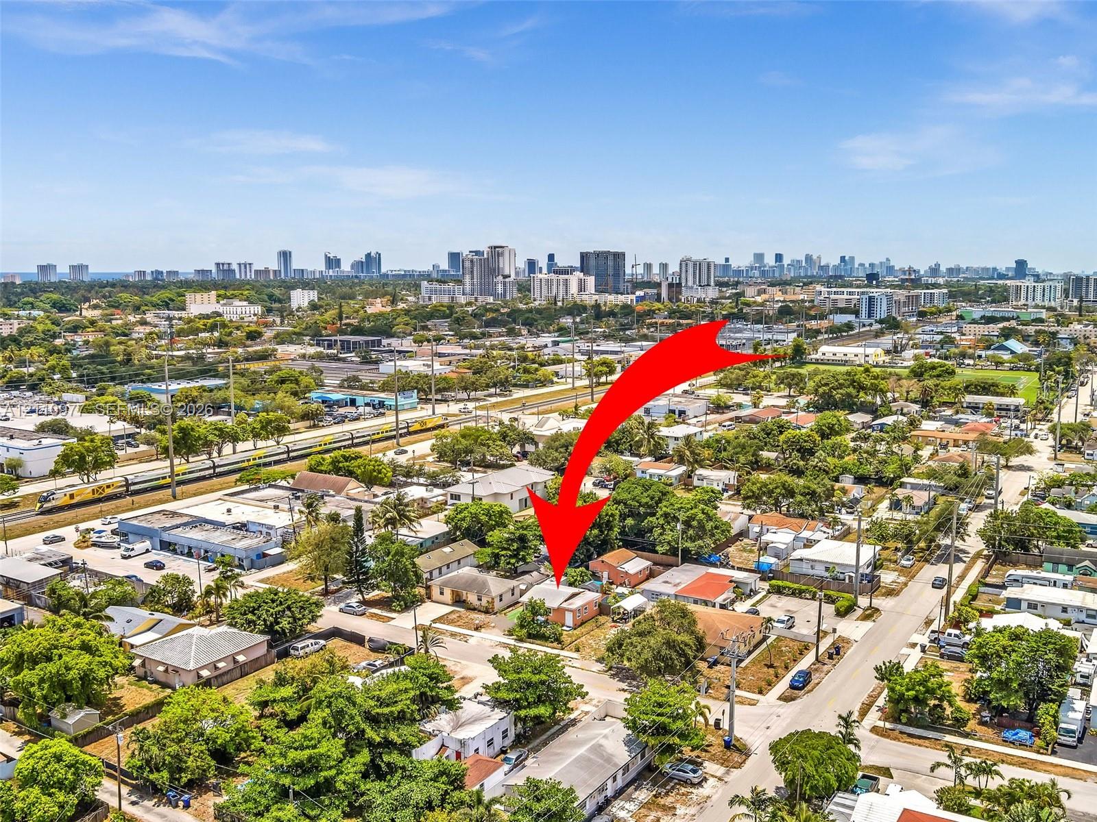 Aerial perspective of a detached single-story residence situated within an urban environment, featuring a hip roof and established surrounding greenery