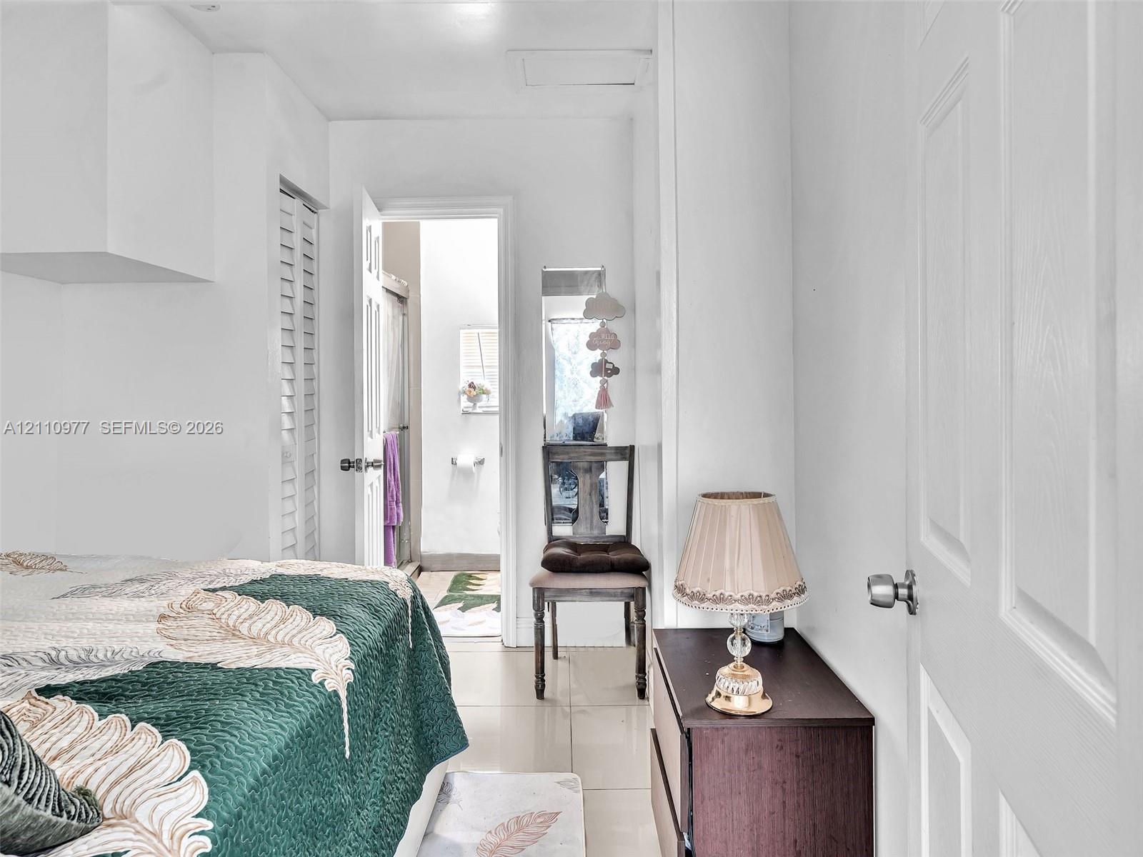 Neutral-toned tile flooring, louvered closet doors, and a six-panel interior door