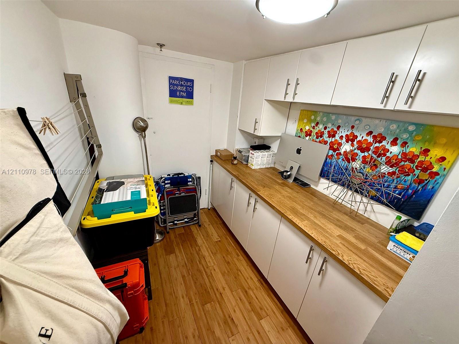 Built-in white cabinetry with stainless steel hardware, wood-finish countertop, and wood-finish flooring