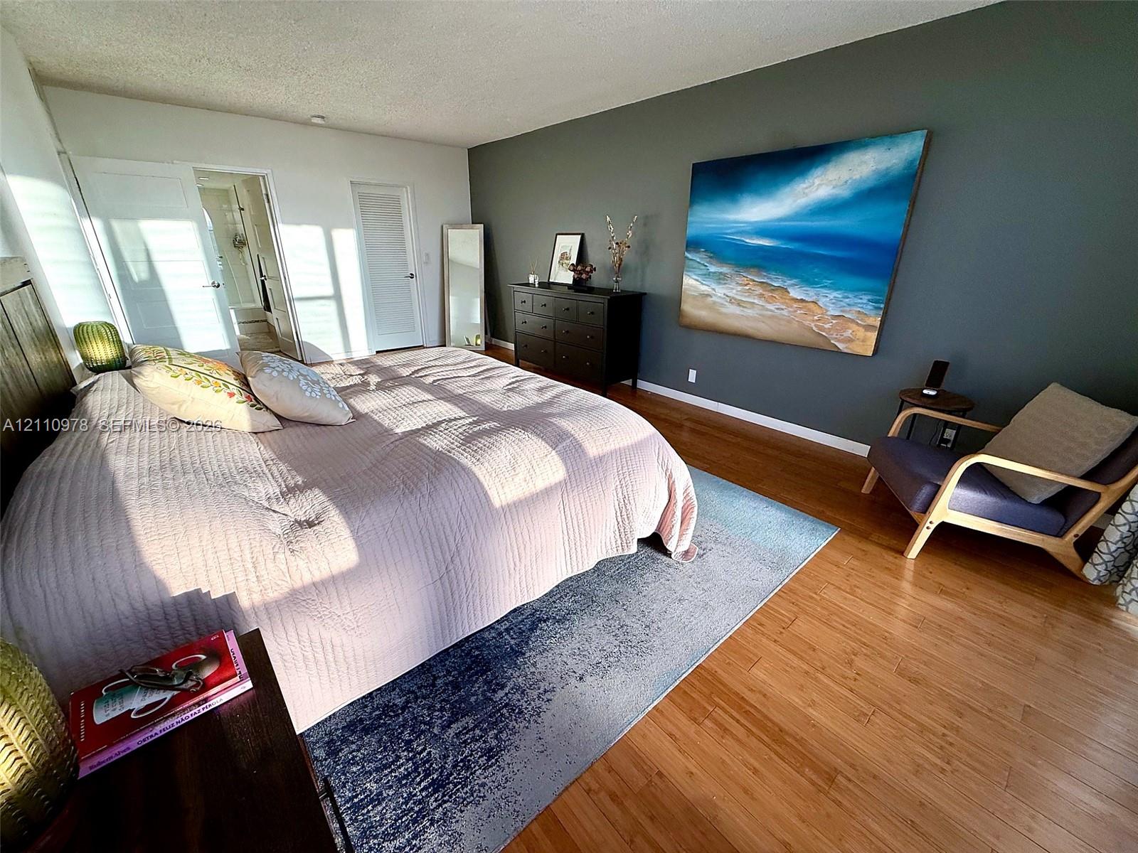 Bedroom featuring wood-finish flooring, a dark-toned accent wall, and multiple closet doors