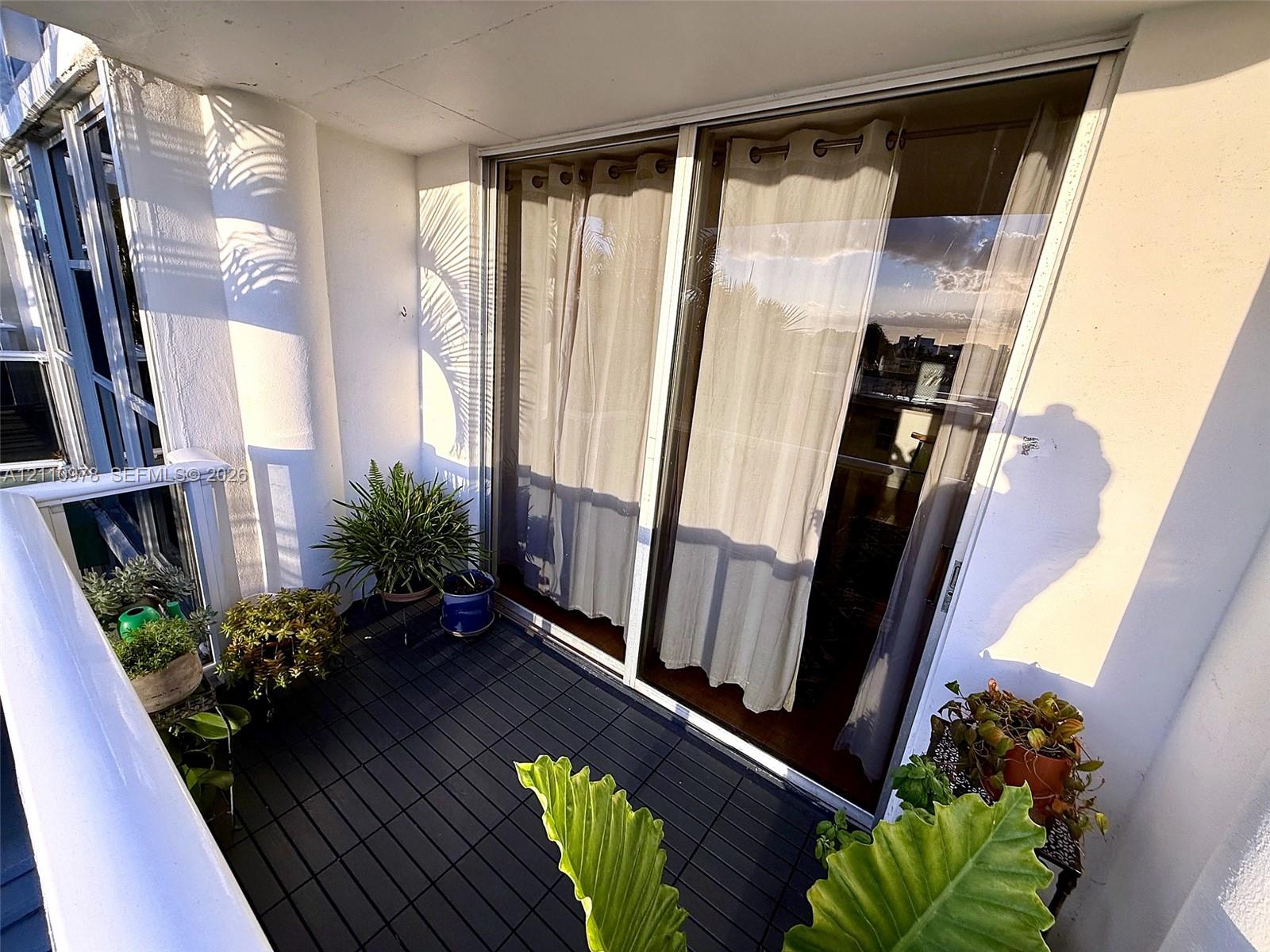 Private balcony featuring a dark-toned modular tile floor, sliding glass door, and a white metal railing