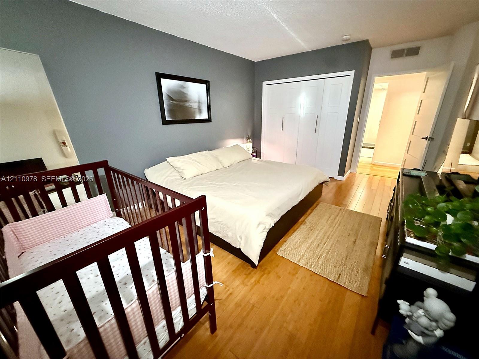 Room featuring wood-finish flooring and a built-in closet with white paneled doors
