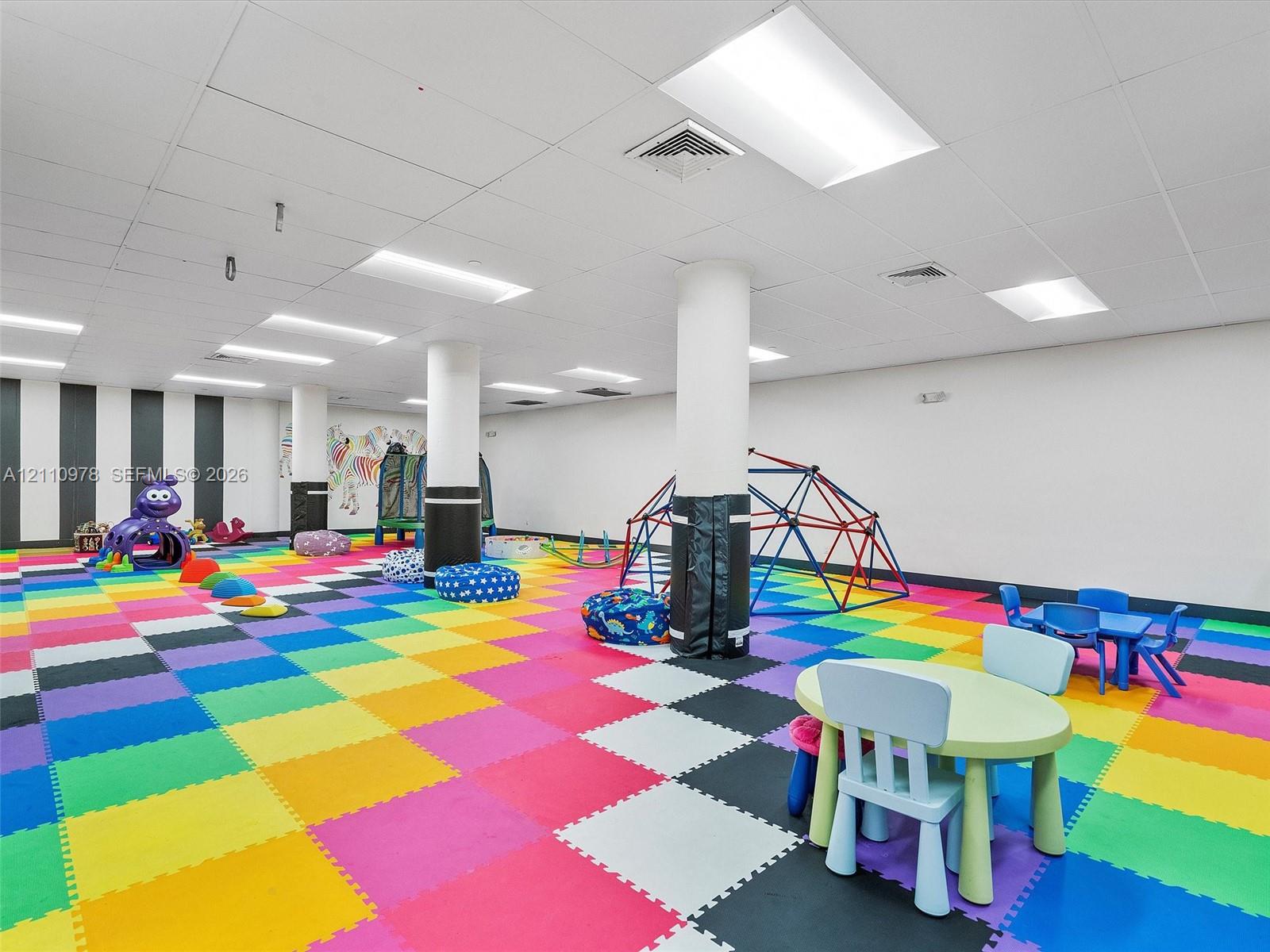 Open-concept interior space featuring high-contrast wall accents, modular foam flooring, structural support pillars with protective padding, and recessed overhead lighting