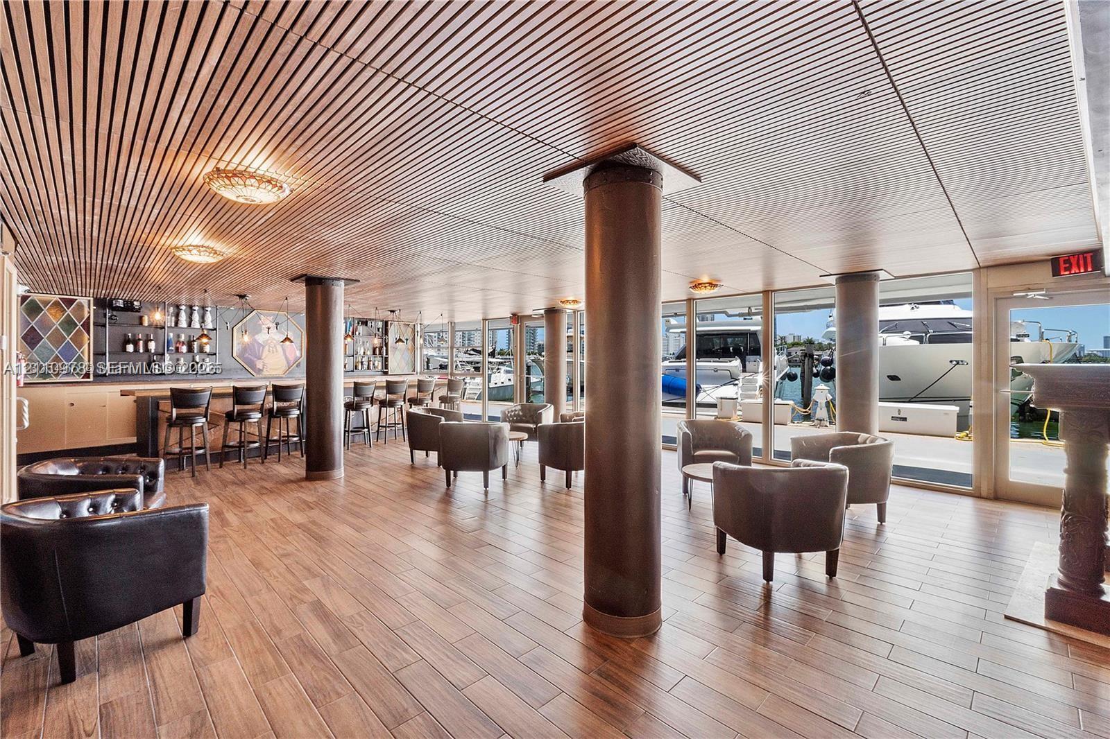 Custom bar area featuring wood-finish flooring, slatted wood ceiling, cylindrical support columns, and floor-to-ceiling glass paneling