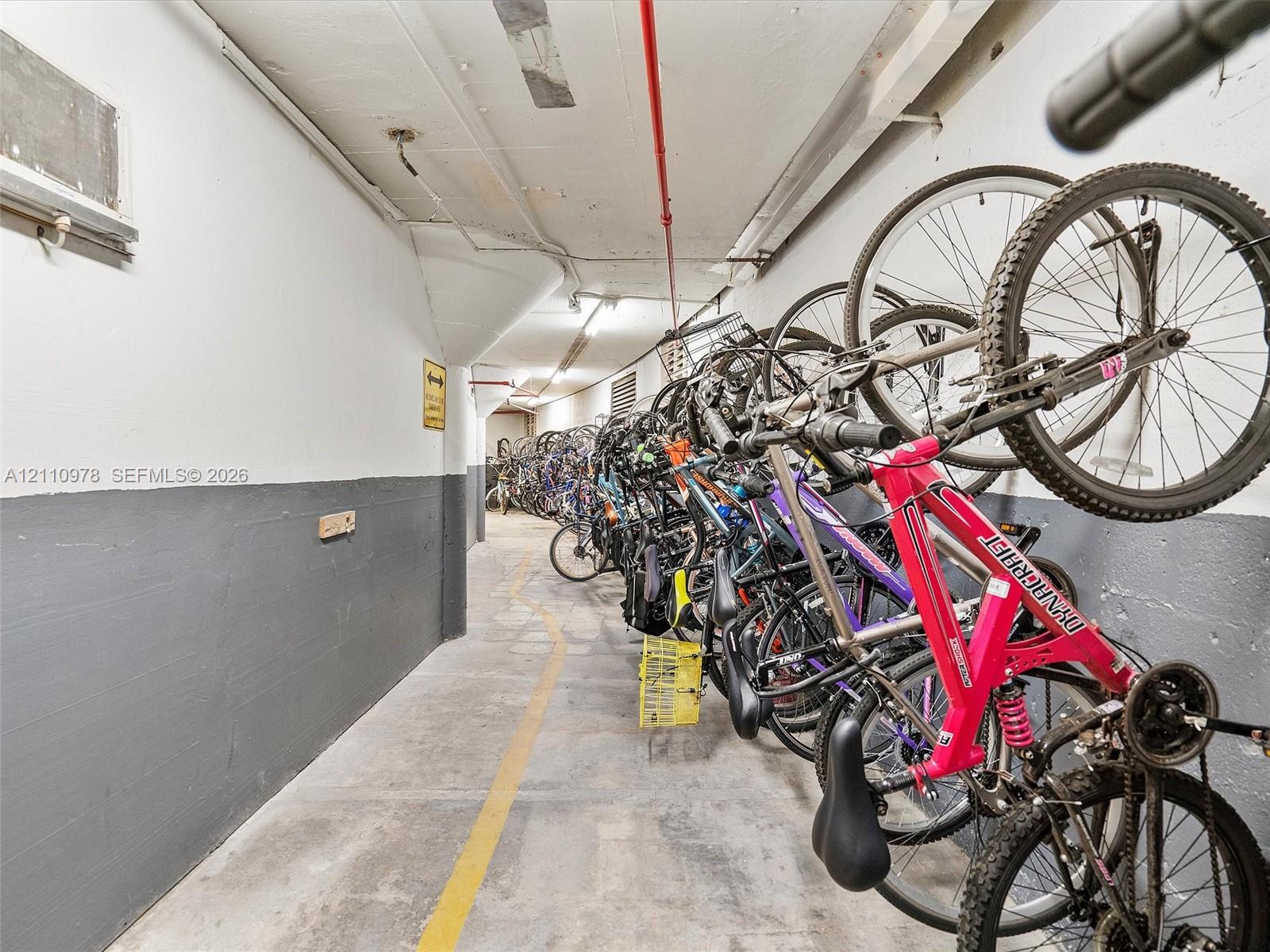 Dedicated storage area featuring concrete flooring, two-tone painted wall surfaces, and integrated wall-mounted bicycle racking