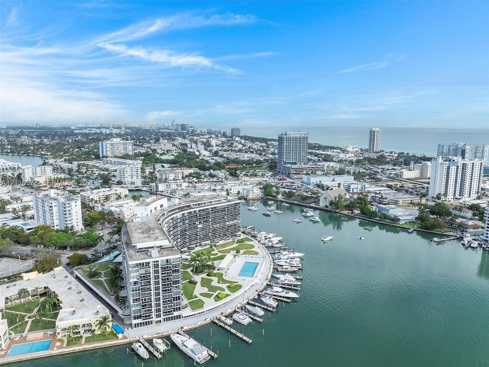 Waterfront high-rise building featuring a private marina, paved outdoor recreation area, swimming pool, and landscaped grounds