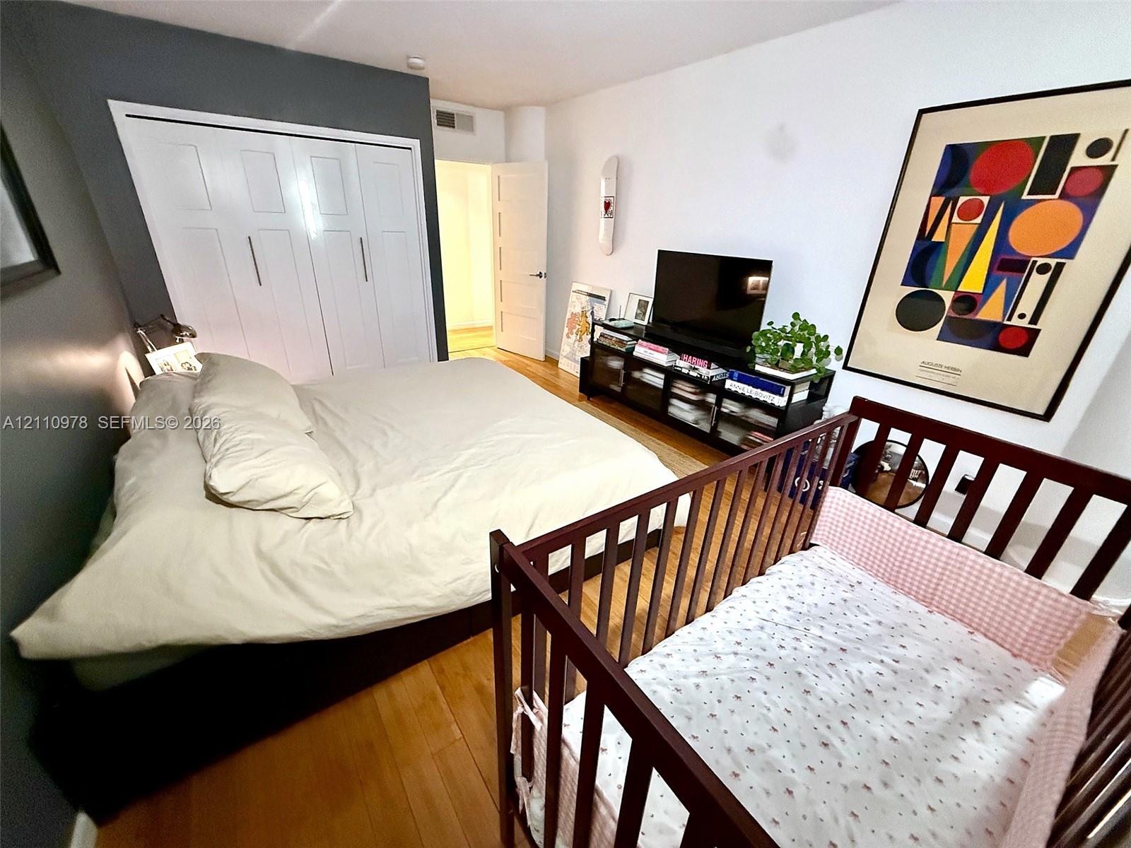 Wood-finish flooring, white paneled closet doors, and a charcoal accent wall