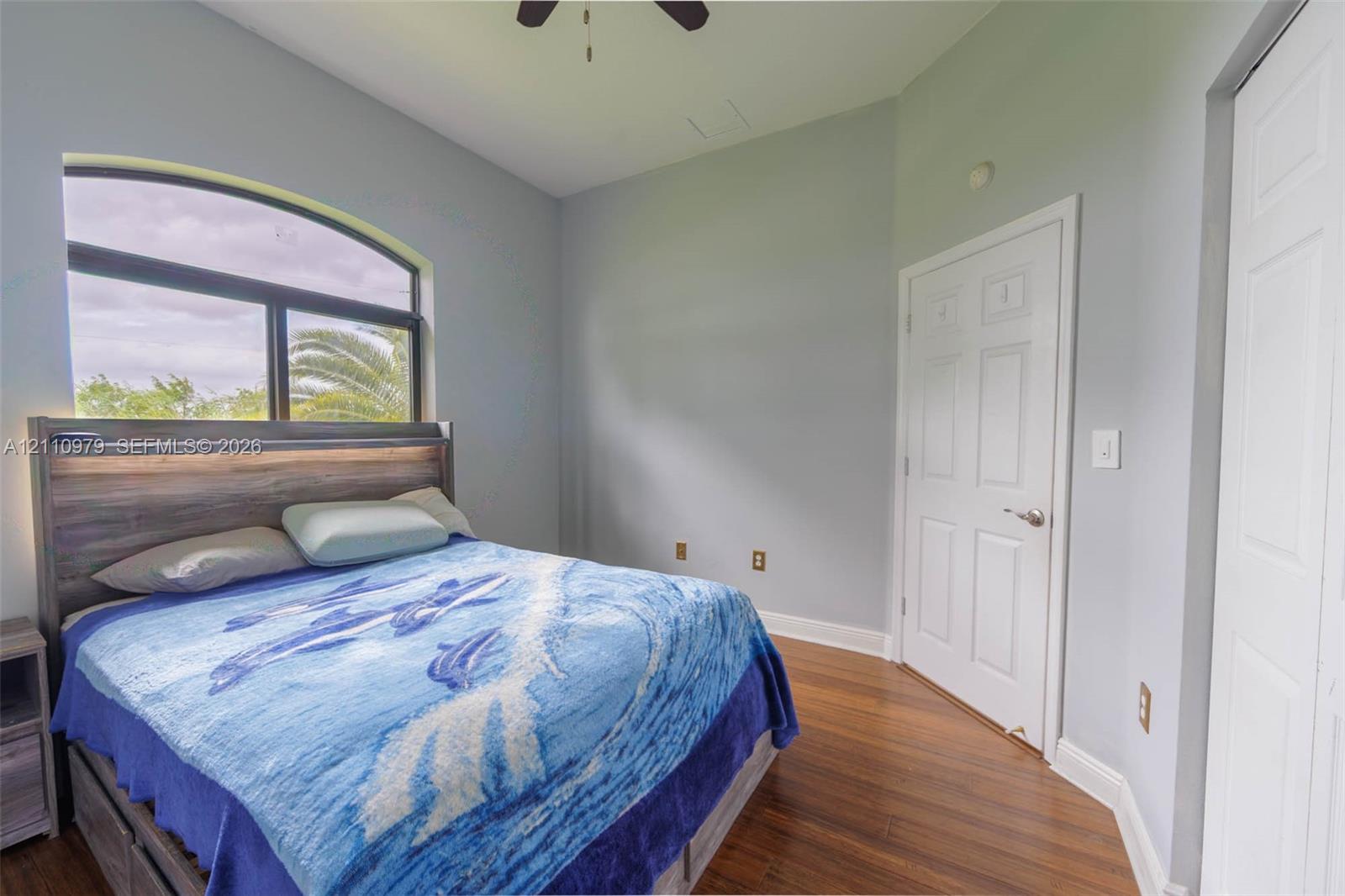 Arched window, wood-finish flooring, high ceilings, ceiling fan, and six-panel interior doors