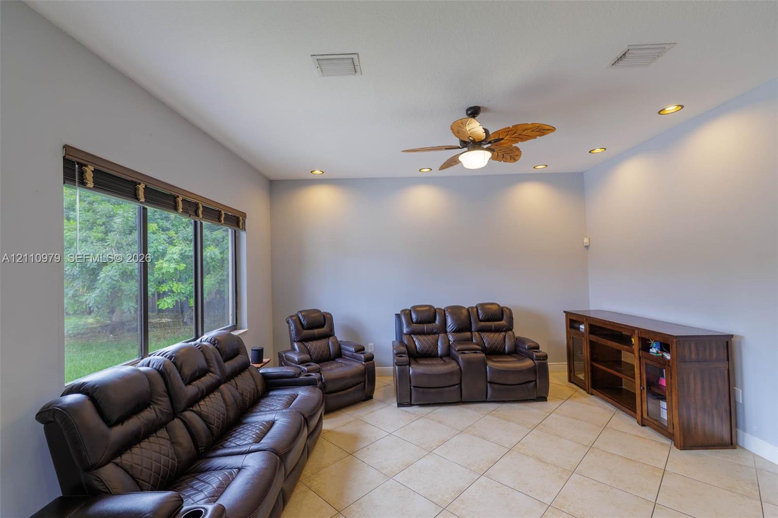 Neutral interior featuring large-format tile flooring, recessed lighting, and a ceiling fan with leaf-shaped blades