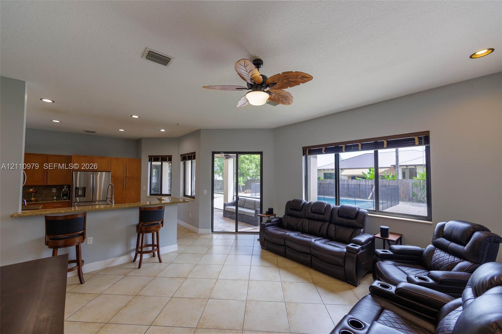Open-concept living space featuring ceramic tile flooring, recessed lighting, and a kitchen breakfast bar with stone countertops