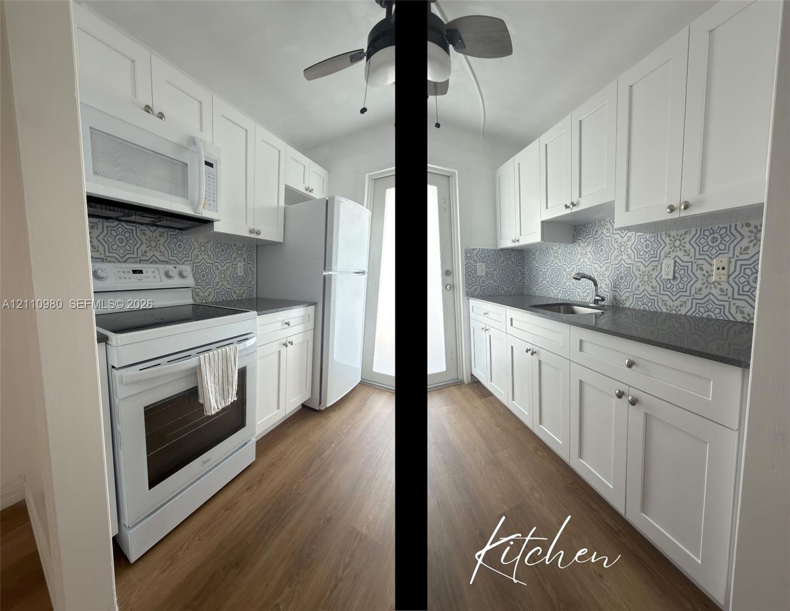 Galley kitchen featuring white shaker-style cabinetry, decorative patterned backsplash, dark solid-surface countertops, wood-finish flooring, and stainless steel undermount sink