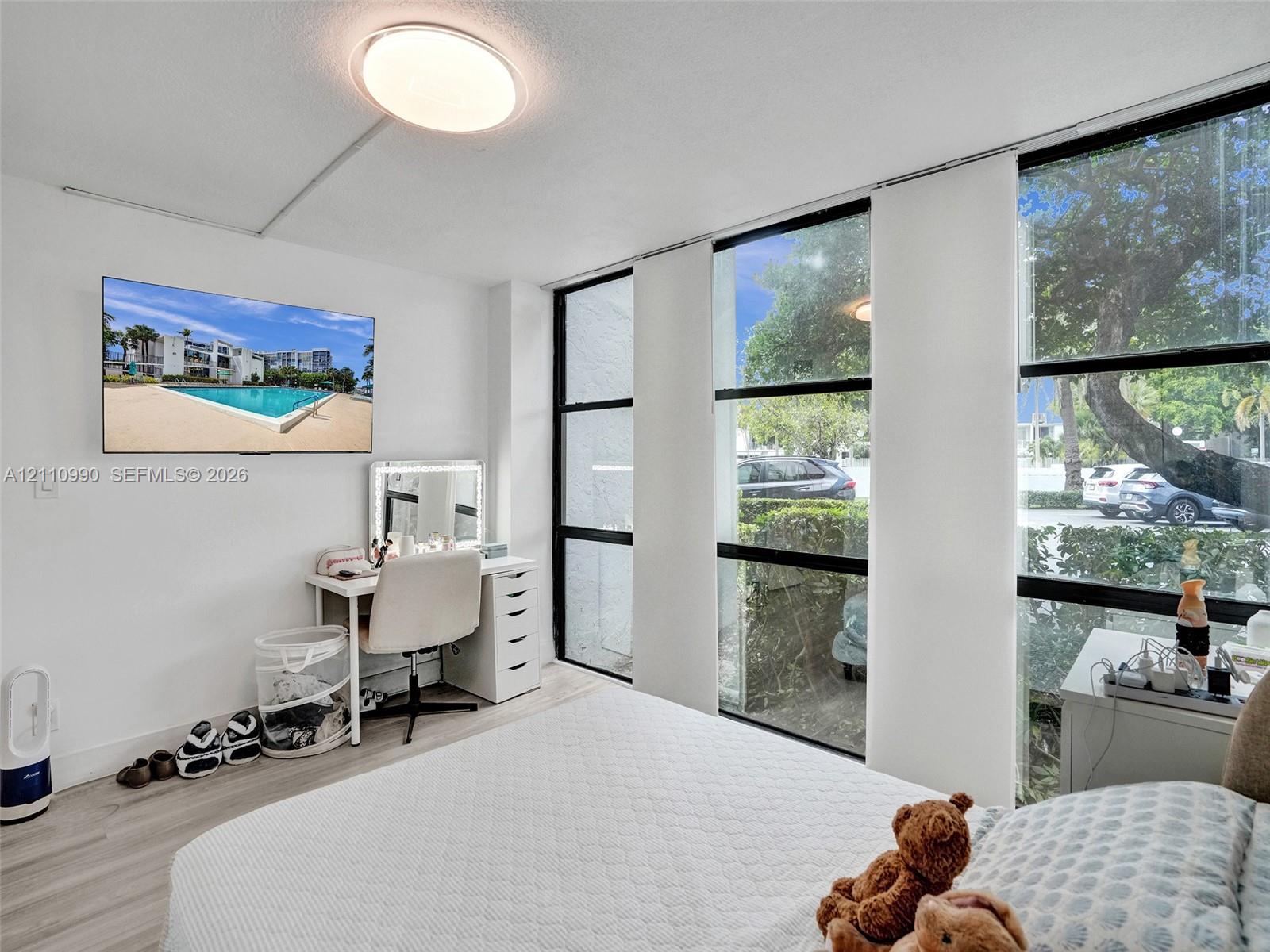 Floor-to-ceiling windows with black frames, wood-finish flooring, and flush-mount ceiling lighting
