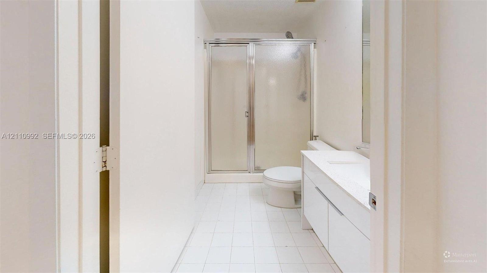 Bathroom featuring a white vanity cabinet with a stone countertop, an integrated sink, a walk-in shower with a glass enclosure, and ceramic tile flooring