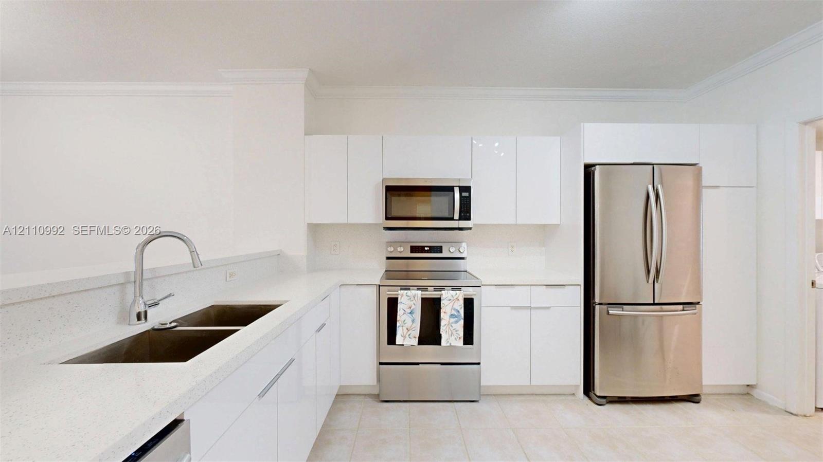 Kitchen featuring white high-gloss cabinetry, stone-finish countertops, stainless steel appliances, and a double-basin undermount sink with a gooseneck faucet