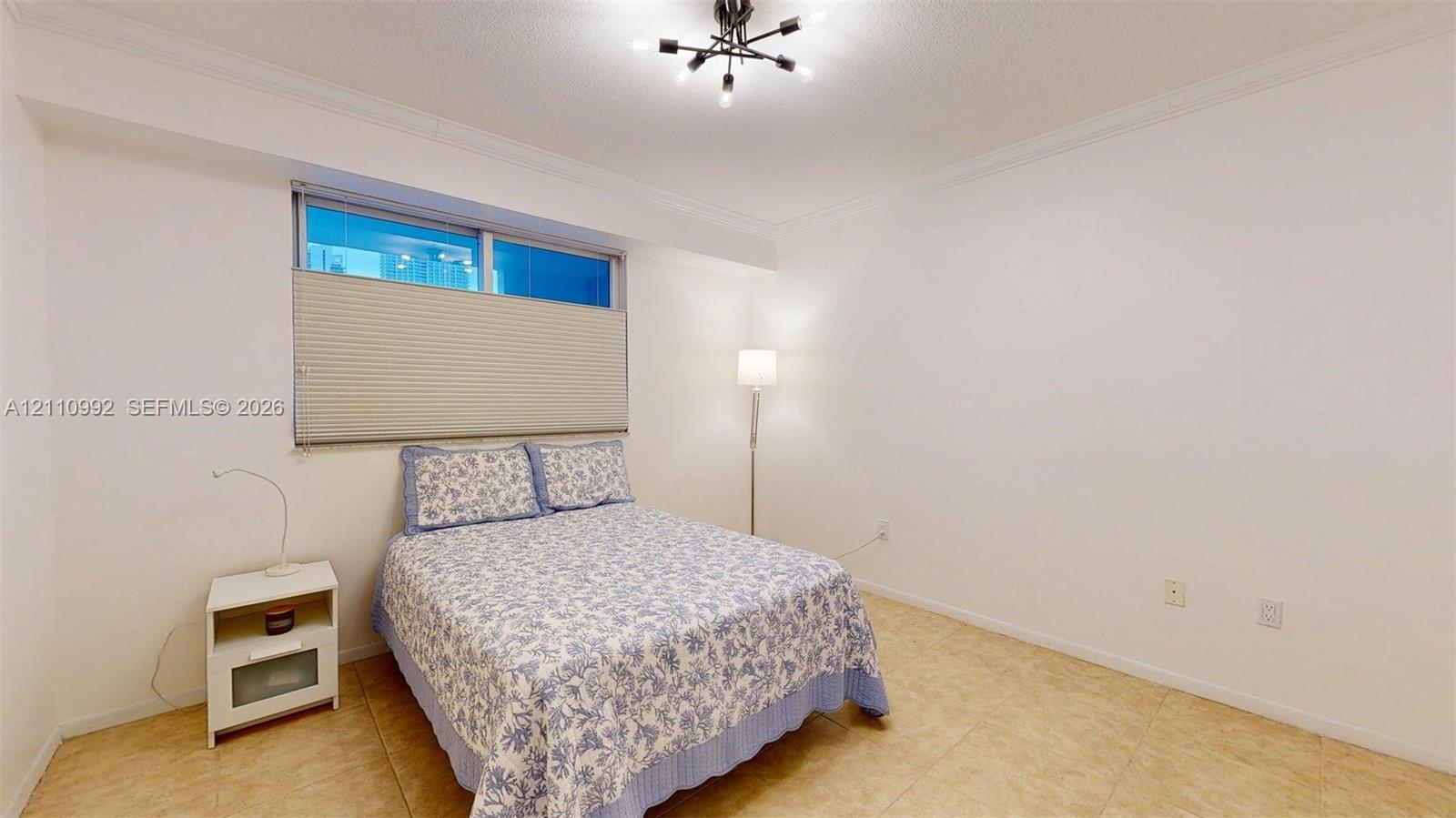 Spacious room featuring tile flooring, crown molding, and a modern multi-arm ceiling light fixture