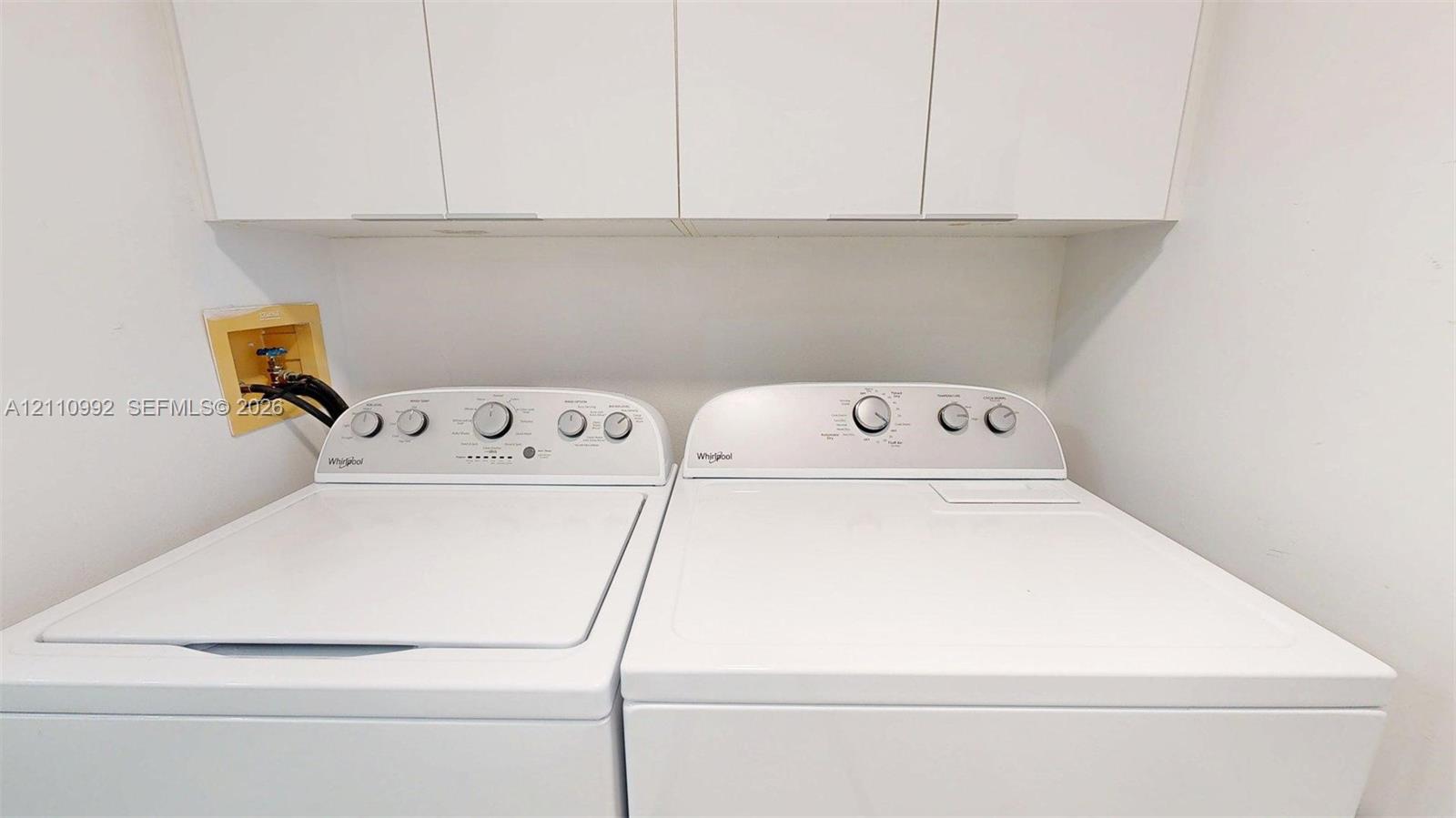 Laundry area featuring white cabinetry and built-in washing machine and dryer