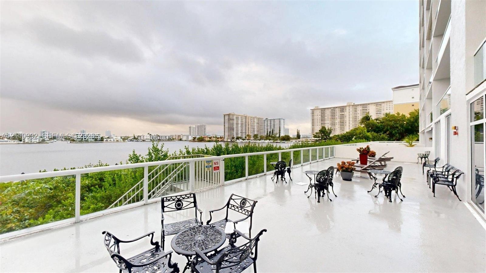 Expansive terrace featuring smooth flooring, metal railings with glass panels, and water-facing orientation
