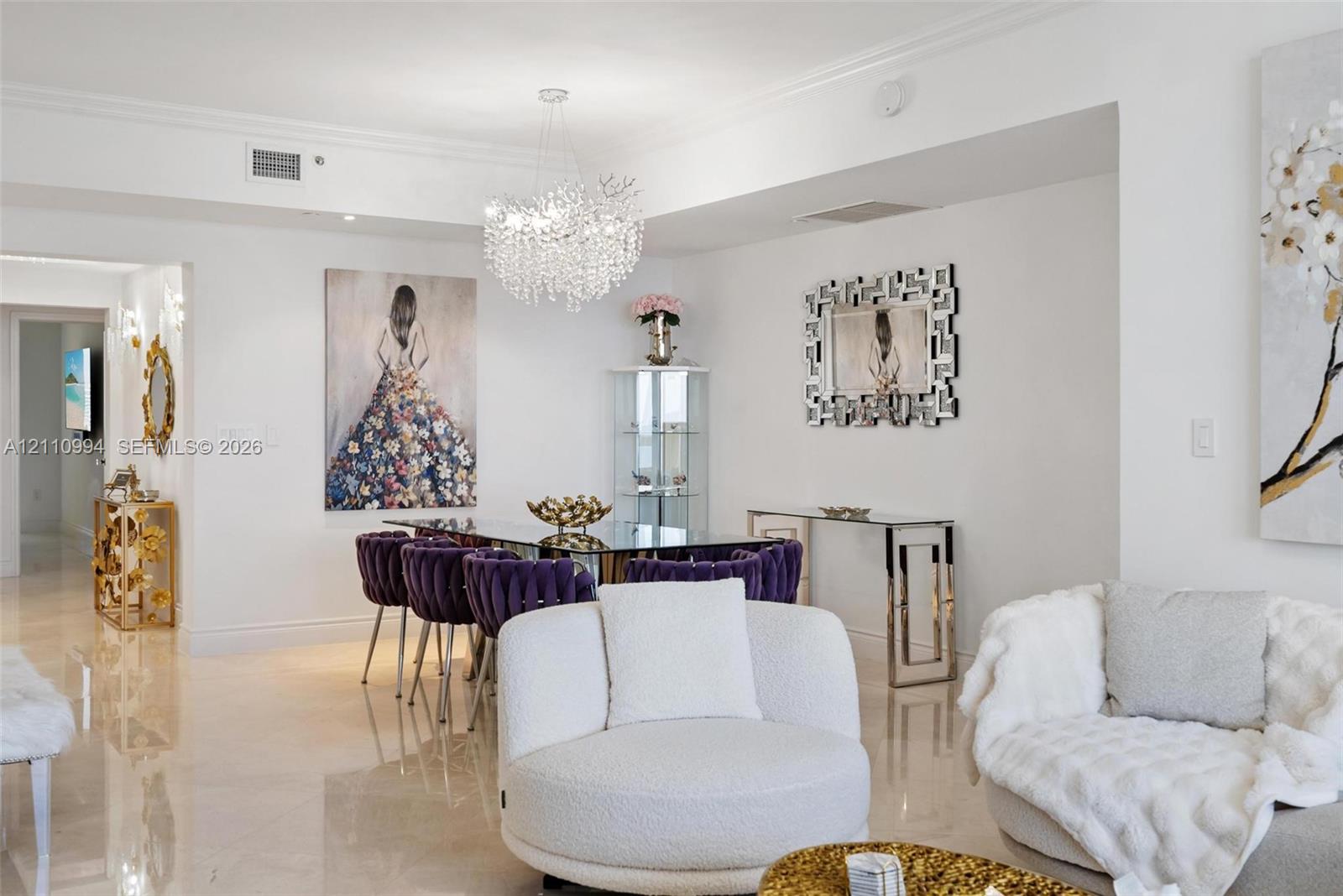 Polished stone flooring, intricate crystal statement chandelier, crown molding, and recessed wall niche