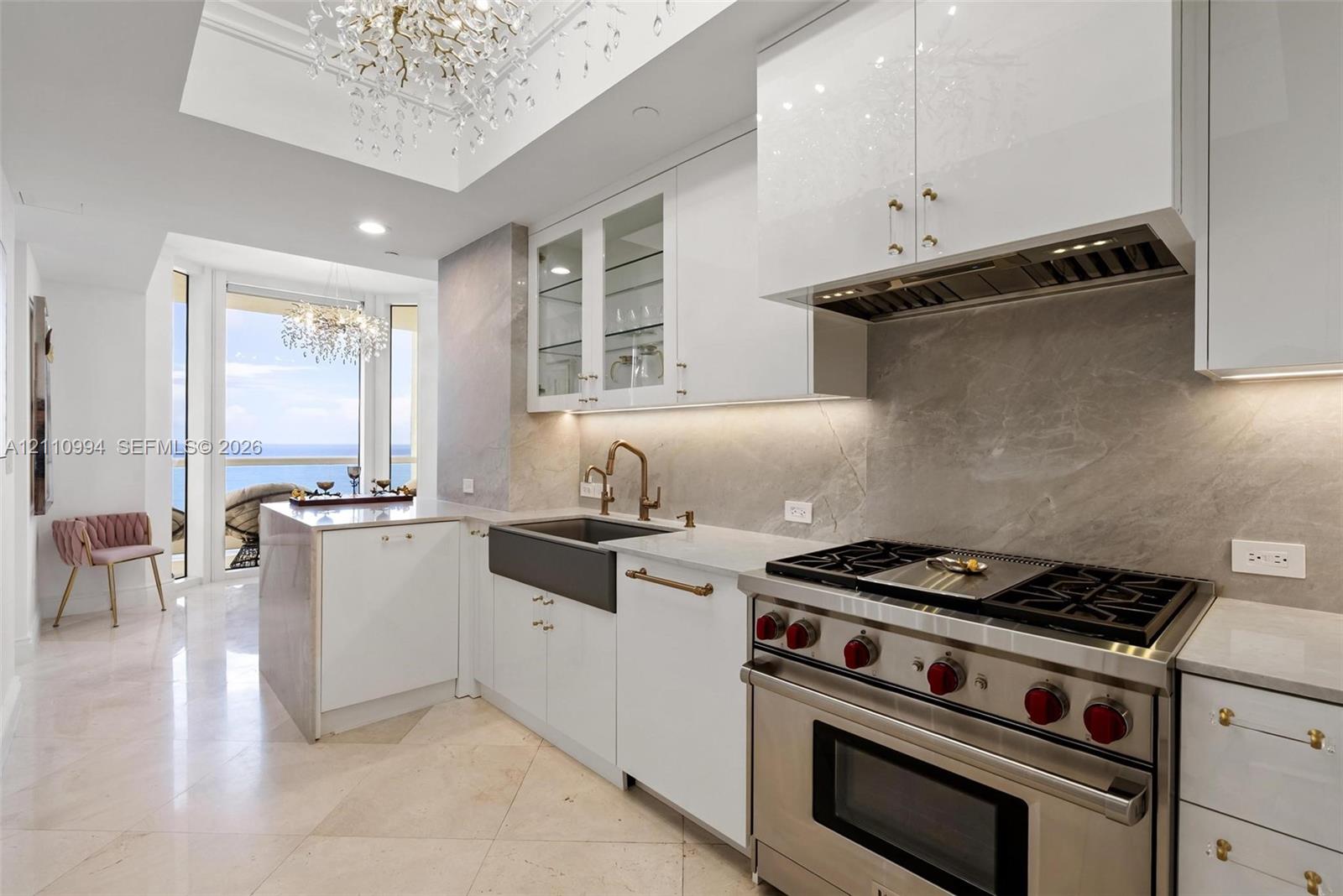 Chefs kitchen featuring custom white cabinetry, stone slab backsplash, farmhouse-style apron sink, professional-grade stainless steel range, and stone flooring