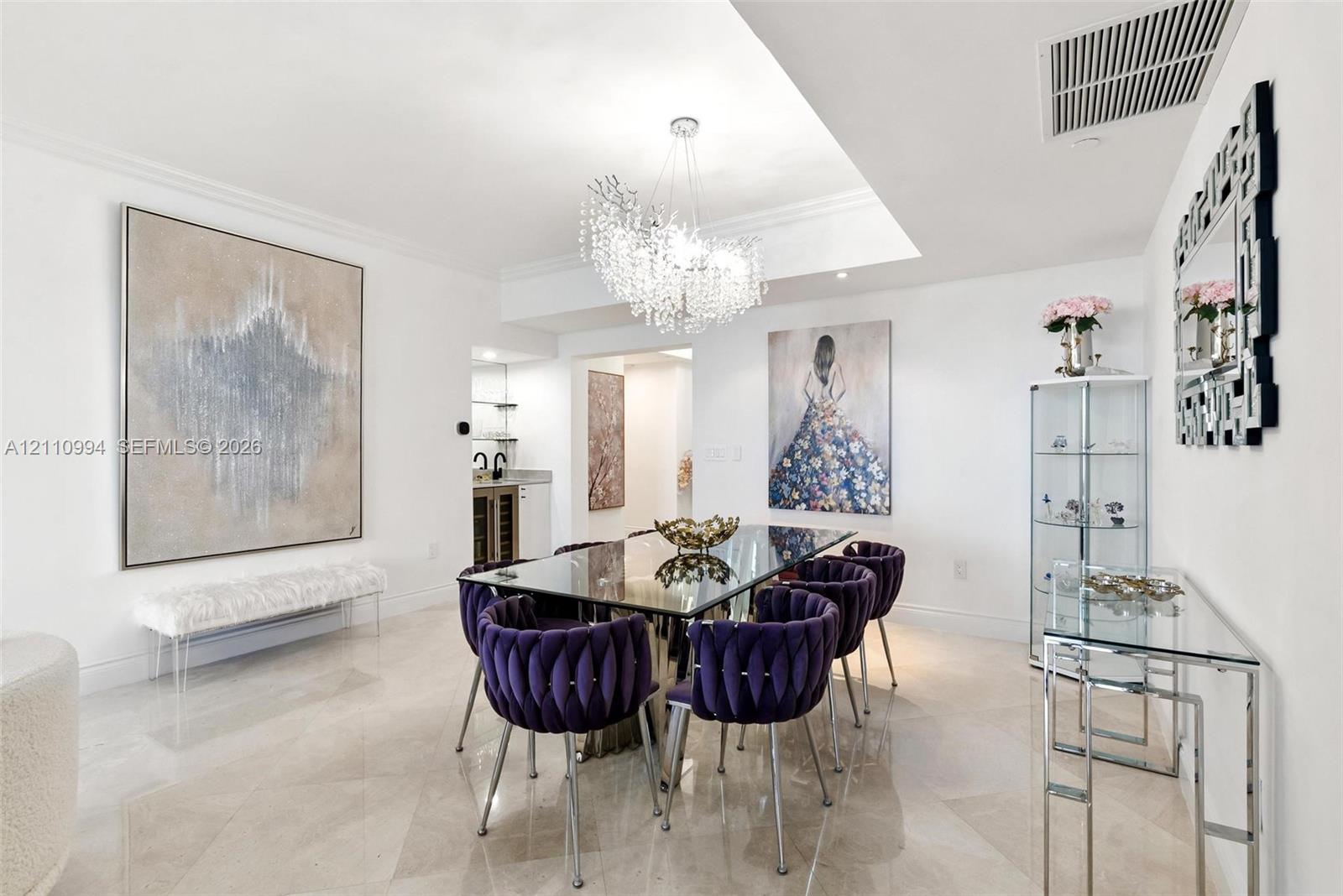 Dining area featuring polished stone tile flooring, a recessed ceiling design, and a tiered crystal chandelier