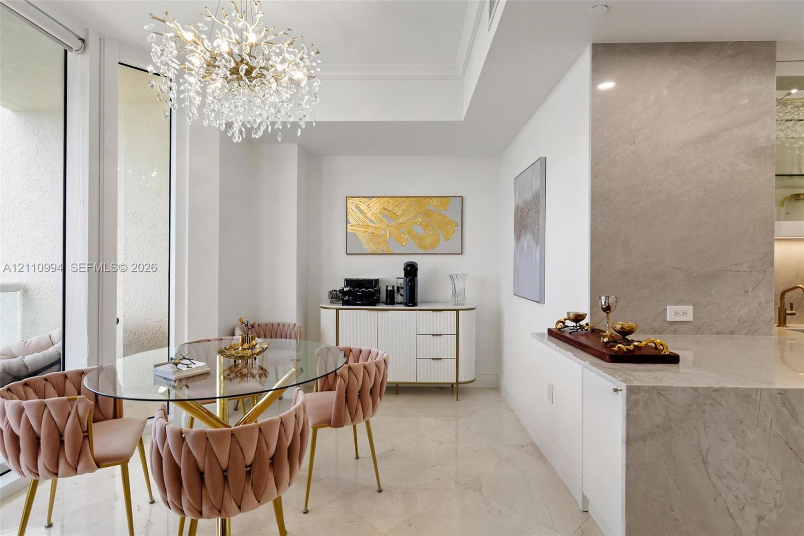 Large-format stone tile flooring, statement crystal chandelier, neutral-tone stone slab countertop, and floor-to-ceiling glass panel door Large-format stone tile flooring, statement crystal chandelier, neutral-tone stone slab countertop, and floor-to-ceiling glass panel door