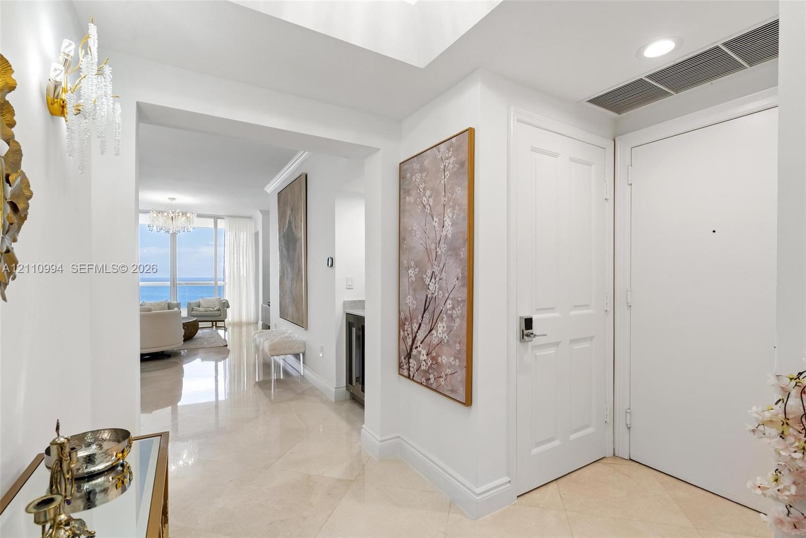 Entryway featuring polished stone flooring, recessed ceiling lighting, a crystal wall sconce, and high-gloss multi-panel doors