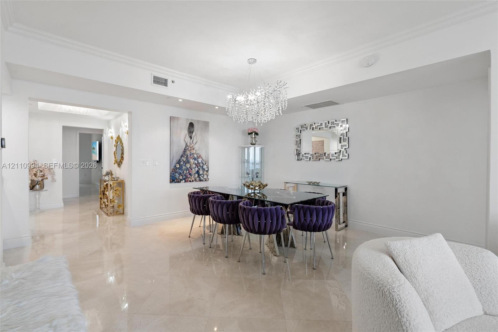 Polished stone flooring, crown molding, and a tiered crystal chandelier