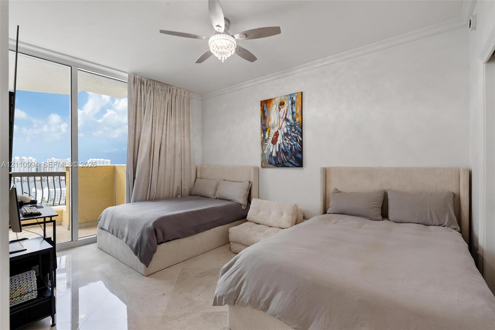Floor-to-ceiling glass sliding doors opening to a balcony, polished stone flooring, crown molding, and a central ceiling fan with an integrated light fixture